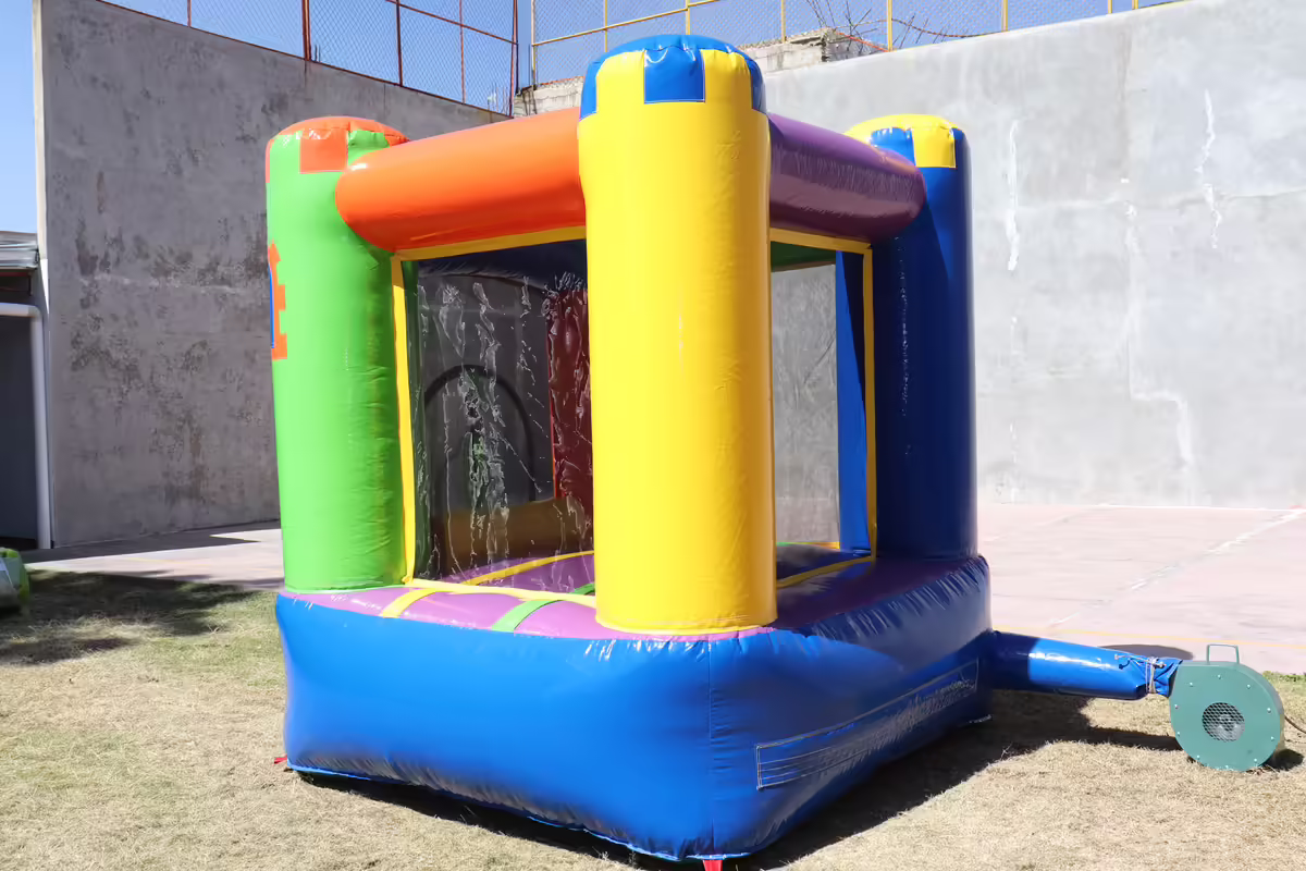Inflable tipo castillo pequeño con techo de colores instalado en un jardín para una fiesta infantil