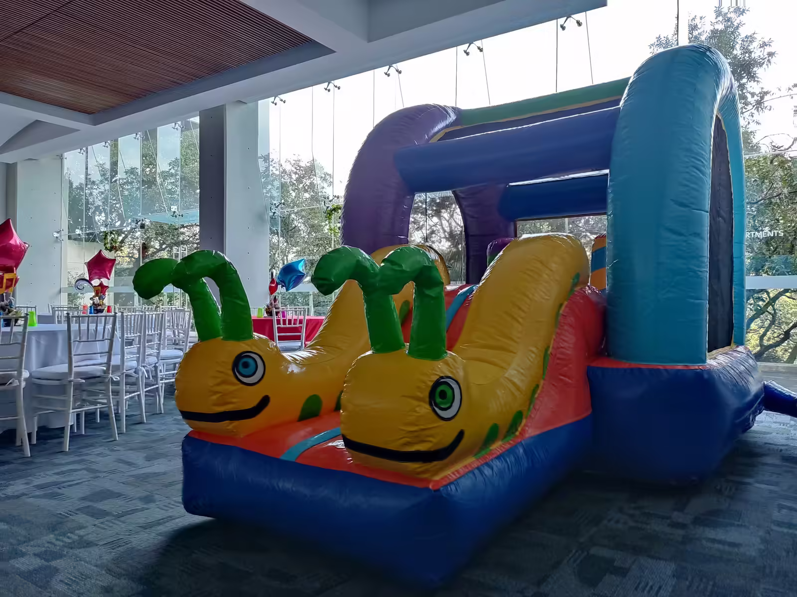 Inflable Gusanitos instalado en una terraza con mesas listas para una fiesta infantil