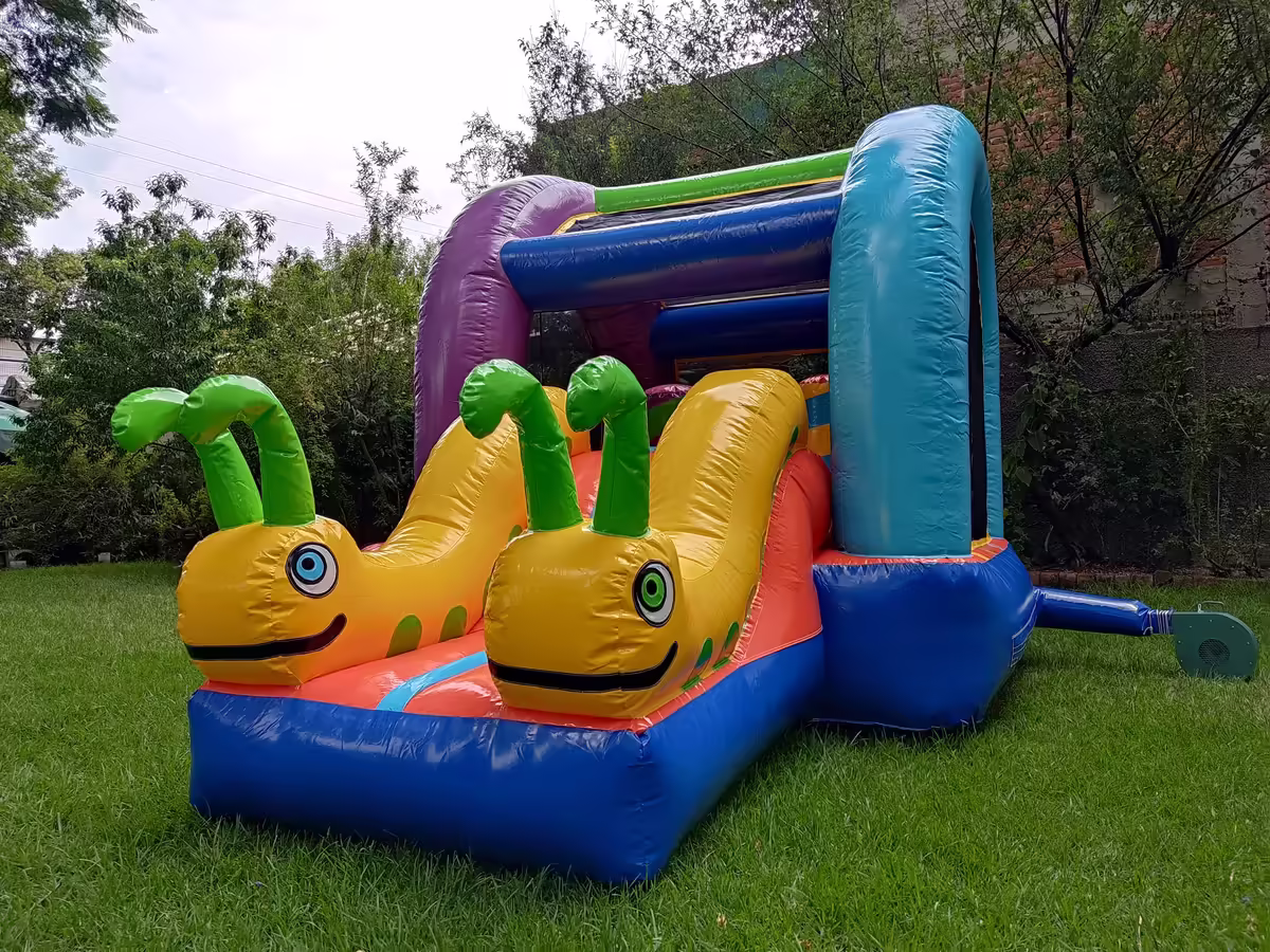 Inflable Gusanitos con figuras de colores instalado sobre pasto en el jardín de una casa