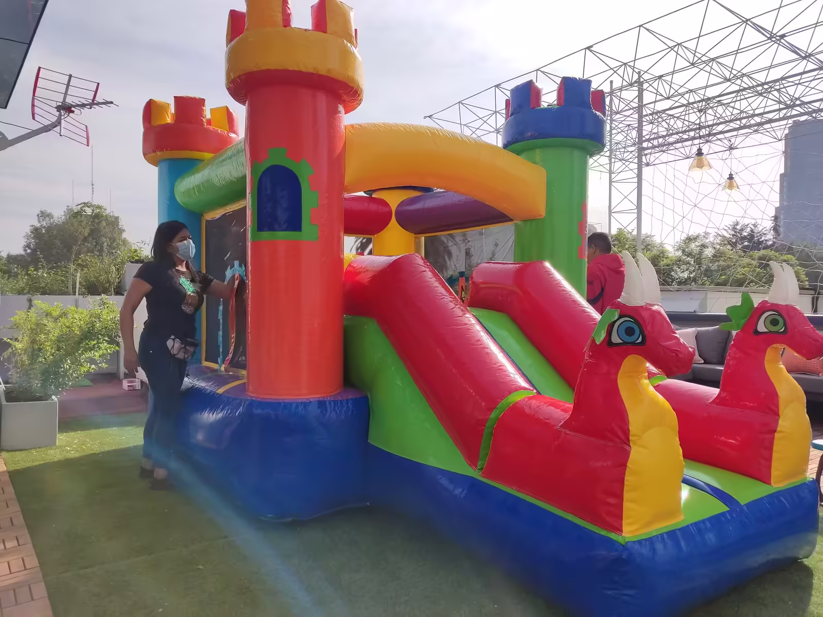 Inflable de dragones con torres y resbaladilla instalado en un jardín para un cumpleaños infantil