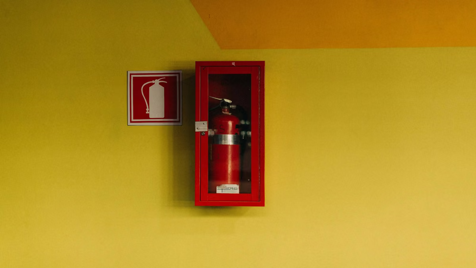 Extintor en su gabinete sobre una pared amarilla