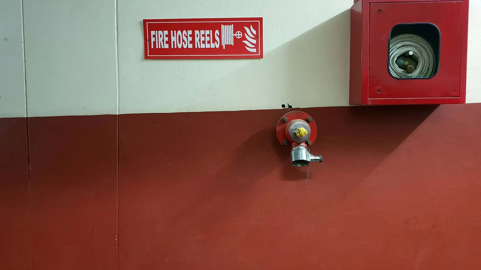 Gabinete de manguera contra incendio y toma de agua en un muro