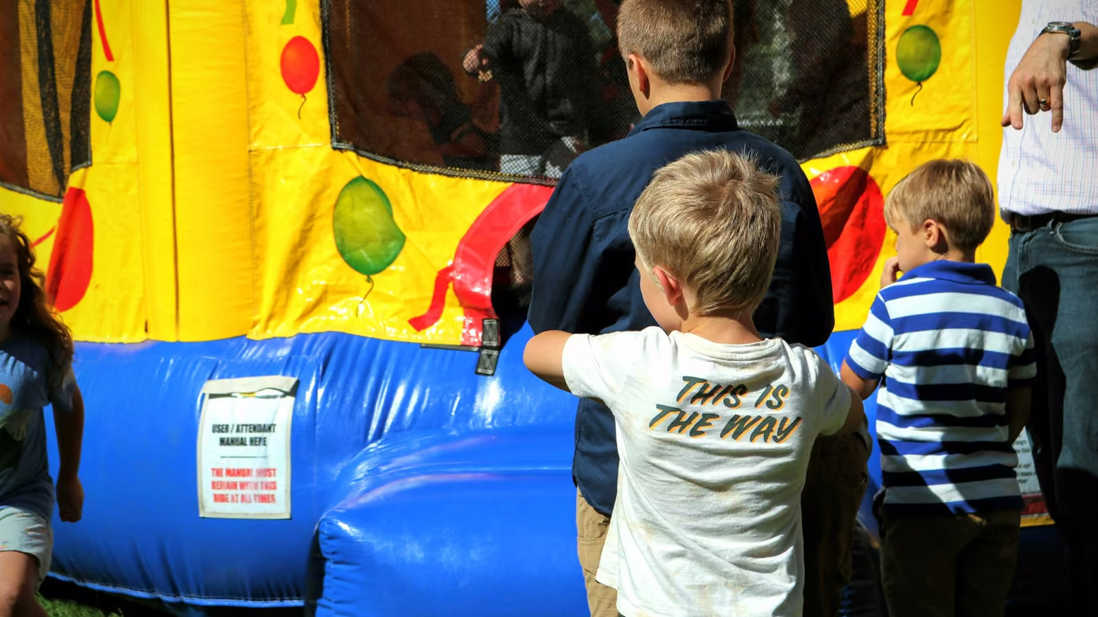 Niños jugando frente a un brincolín inflable en una fiesta