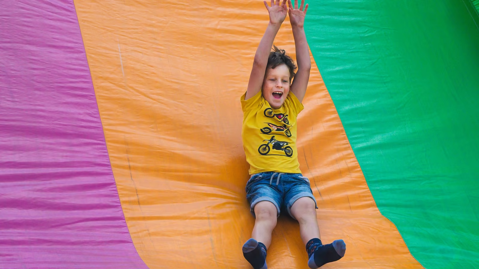 Niño deslizándose por un tobogán inflable de colores