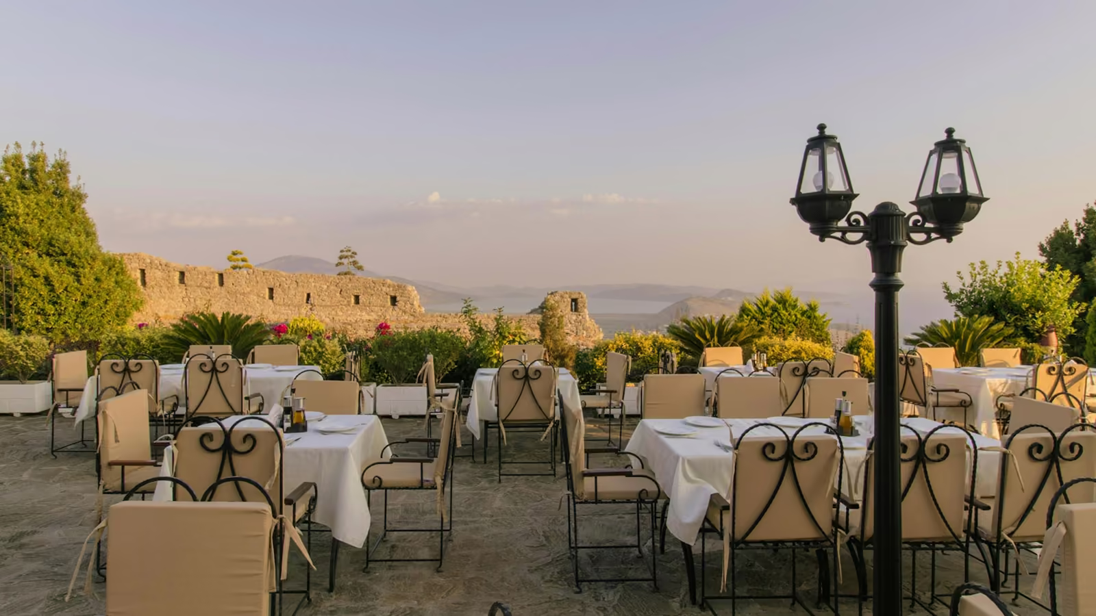 Terraza de restaurante con mesas vestidas de blanco y vista al paisaje