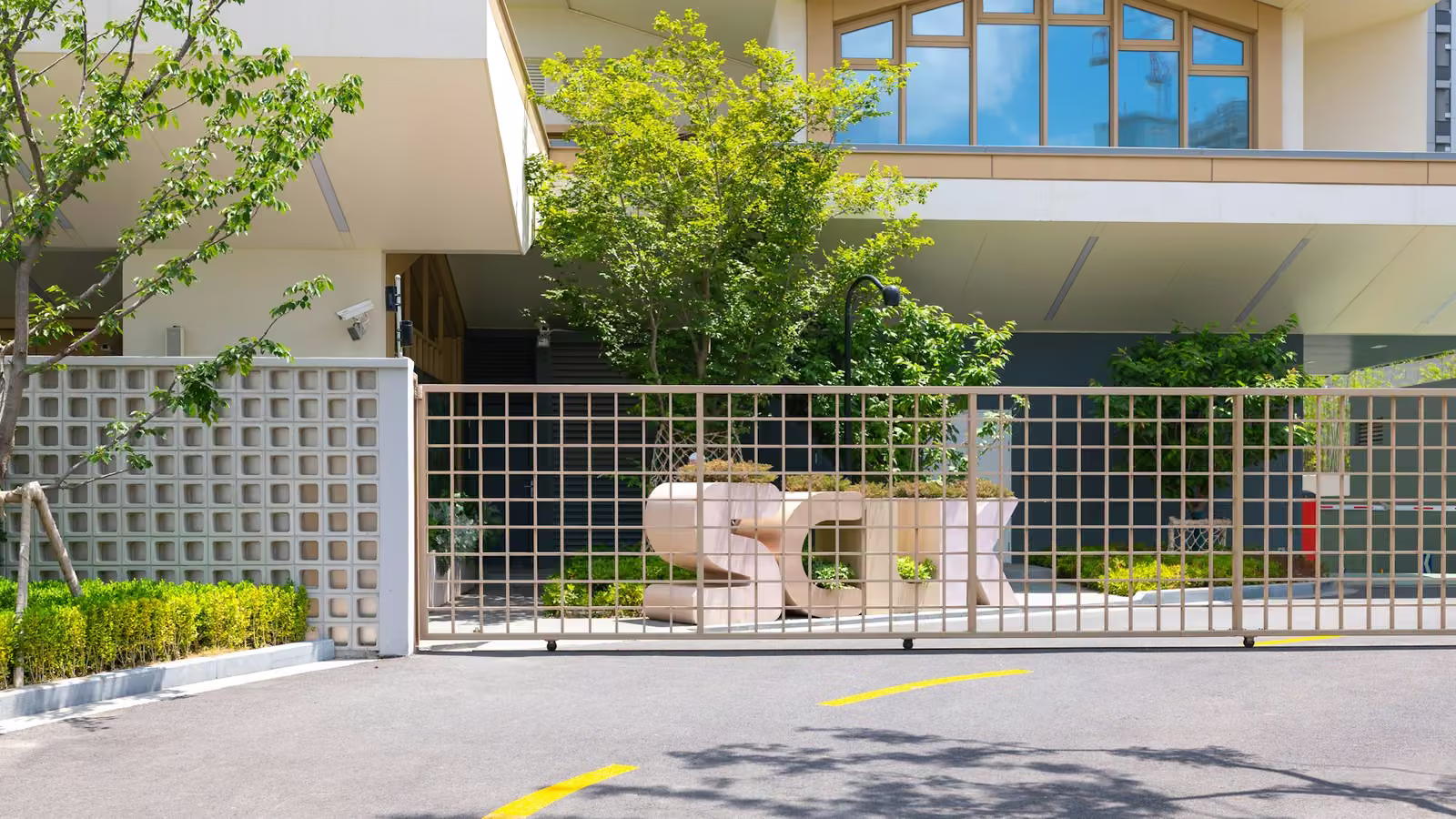 Fachada de un condominio residencial con reja de acceso y jardín