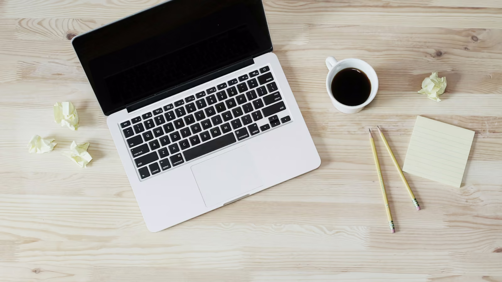 Escritorio con laptop, libreta y café para leer guías de negocio